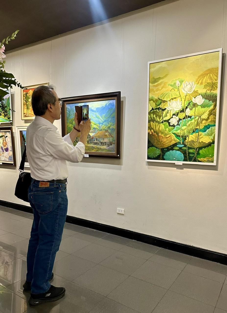 GS.TS Dam Won Kim Chang Bae chụp ảnh bức tranh Sen tại triển lãm.